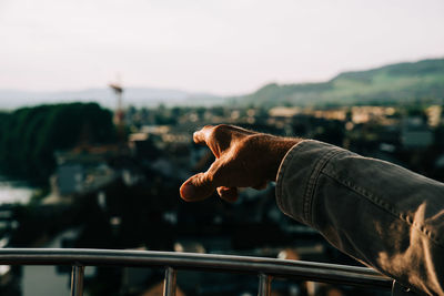 Midsection of man holding railing against sky