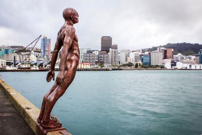 Statue by sea against buildings in city