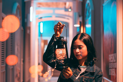 Woman with lit lantern in corridor