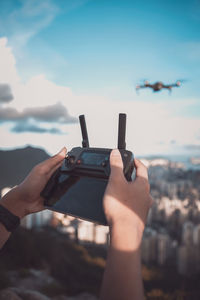 Midsection of person using mobile phone against sky