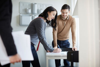 Man looking at woman signing papers of new house