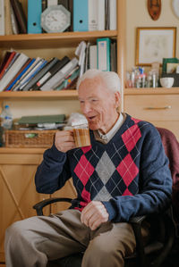 Full length of man sitting on chair at home