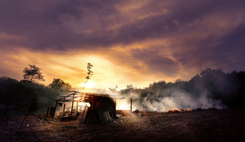 Smoke emitting from land against sky during sunset