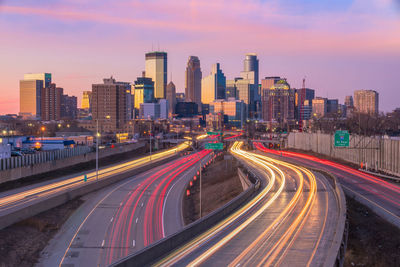 Light trails on road amidst buildings against sky in city