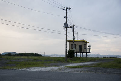 Electricity pylon by road against sky