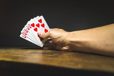 Cropped image of hand holding cards on table