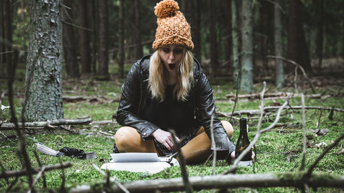 Young woman sitting on tree trunk in forest