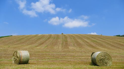 Hay bales on field against sky