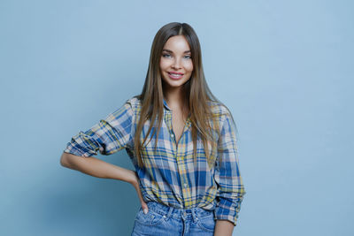 Young woman standing against blue background