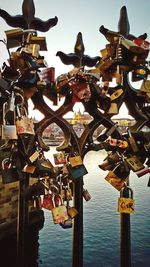 Close-up of padlocks hanging on river against sky