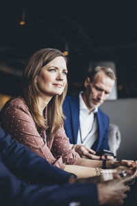 Female entrepreneur sitting with male coworkers at workplace