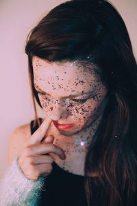 Woman with glitter on face picking nose