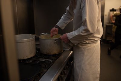 Midsection of man holding ice cream in kitchen