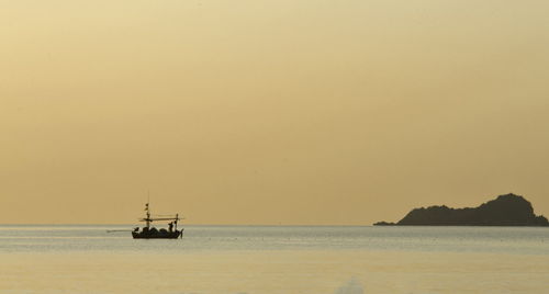 Silhouette sailboat in sea against sky during sunset