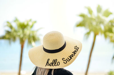 Close-up of man with text on palm tree against sky