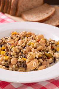 Spelled, chickpea, tuna and corn salad arranged on rustic table with bread