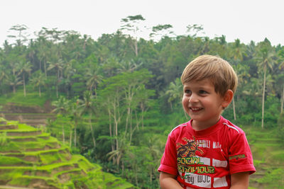 A boy smiles against the background of rice fields in bali