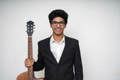 Portrait of smiling young man standing against wall