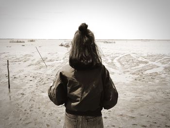 Rear view of woman standing on beach against sky