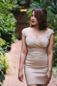 Beautiful young woman standing against plants