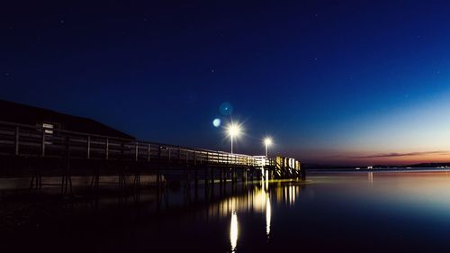 Illuminated bridge against sky at night