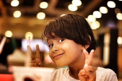 Portrait of smiling girl showing peace sign in restaurant 