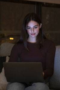 Portrait of young woman using laptop at home