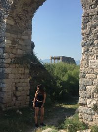 Young woman standing by old ruin