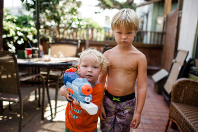 Brothers posing for camera in front yard holding water gun