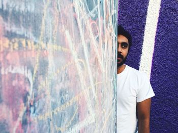 Cropped image of man standing behind graffiti wall