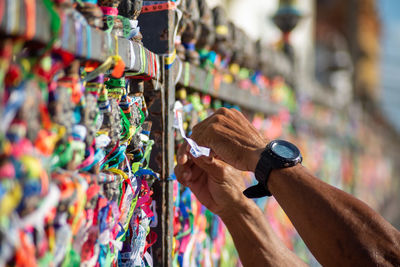 A person's hands are tying a souvenir ribbon on the railing of the senhor do bonfim church