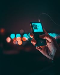 Midsection of person using mobile phone at night
