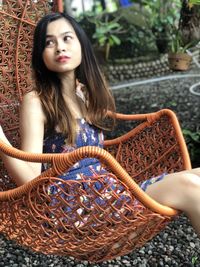 Young woman looking away while sitting outdoors