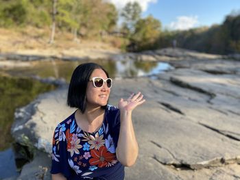 Woman wearing sunglasses standing by river in forest