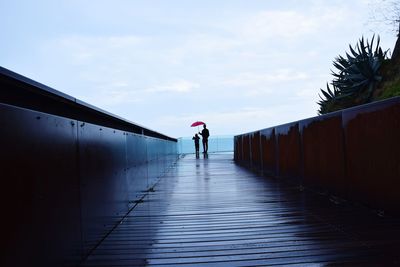 Rear view of woman standing on footpath against sky