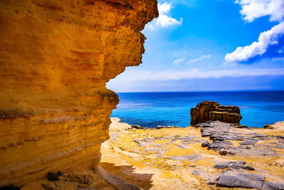 Scenic view of rock formation by sea against sky