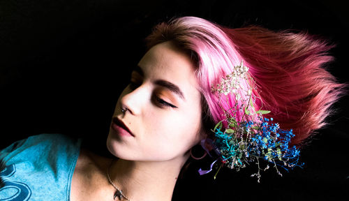 Close-up of young woman against black background