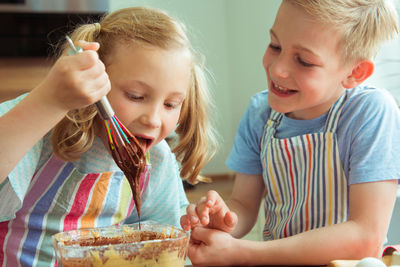 Siblings preparing food on table at home