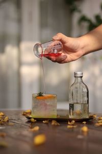 Cropped hand pouring water from bottle on table