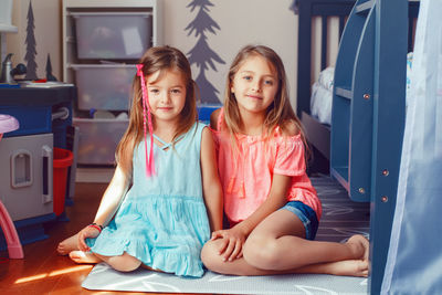 Portrait of cute siblings sitting on floor