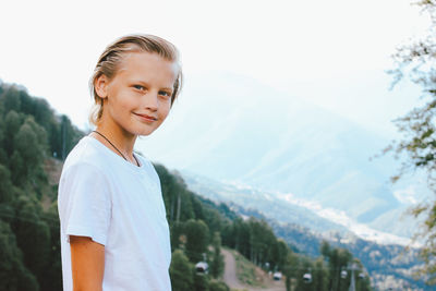 Portrait of boy standing against mountains and sky