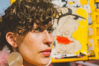 Close-up of thoughtful woman looking away against graffiti on wall