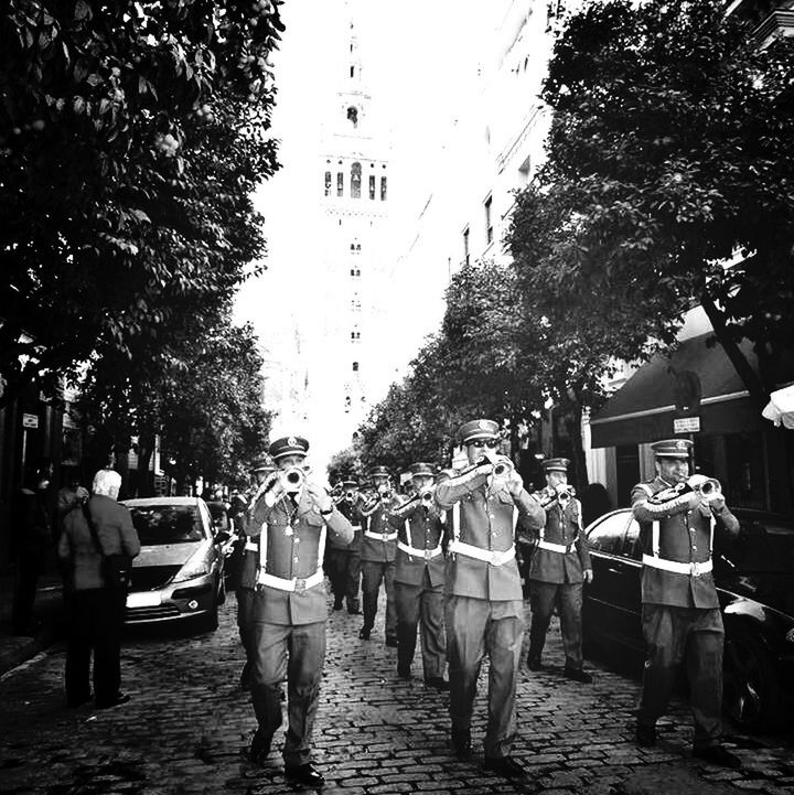 tree, men, person, street, building exterior, transportation, city, lifestyles, walking, architecture, built structure, road, the way forward, city life, medium group of people, large group of people, mode of transport, day, rear view