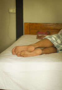 Low section of woman lying on bed