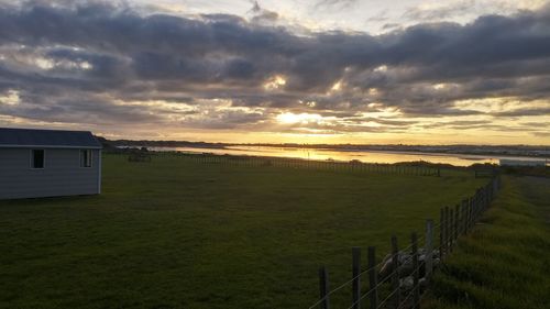 Scenic view of grassy field against cloudy sky