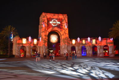 Group of people in front of illuminated building at night