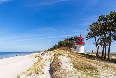 Lighthouse by sea against sky