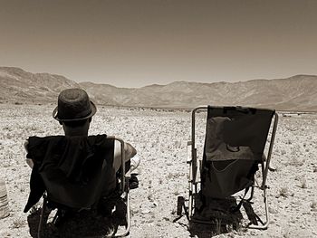 Rear view of man sitting in the desert