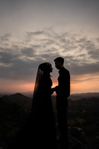 Silhouette couple standing against sky during sunset