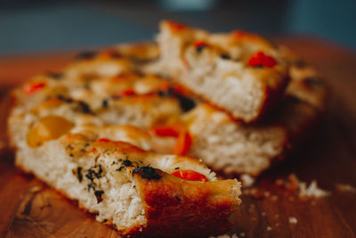 
homemade italian focaccia slices, with tomato and olive oil on a rustic wooden background.